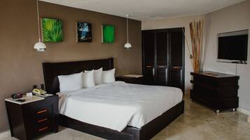 A modern hotel room with a large bed, bedside tables, a desk, and a TV.