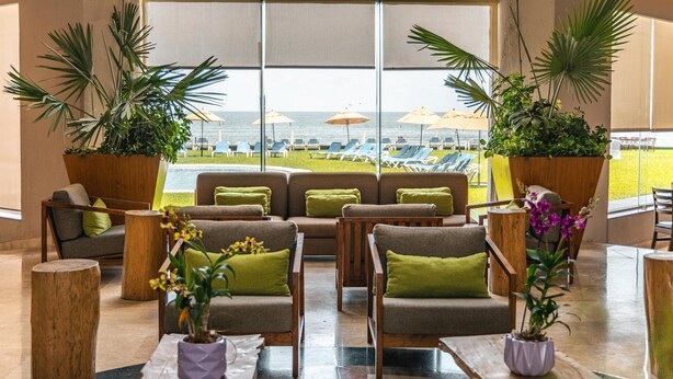 A lounge area with seating, potted plants, and a view of the beach. - Hilton Garden Inn Boca del Rio Veracruz (Boca del Río)