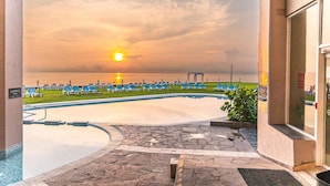 A pool area with lounge chairs and a view of the sunset over the ocean. - Hilton Garden Inn Boca del Rio Veracruz (Boca del Río)