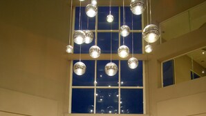 A spacious living area with a high ceiling, large windows, and multiple hanging spherical light fixtures. - Hilton Garden Inn Boca del Rio Veracruz (Boca del Río)