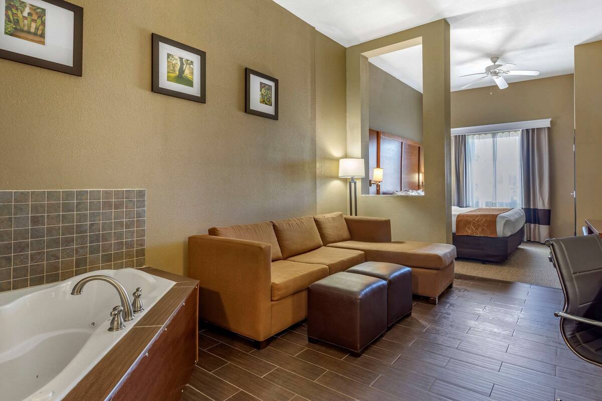 A hotel bathroom with a bathtub, a sofa, and a bed.