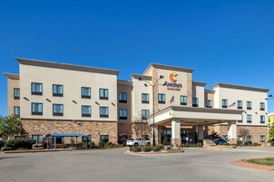 Un hotel Comfort Suites con entrada cubierta, múltiples ventanas y fachada de piedra.