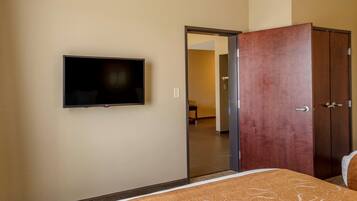 A hotel room with a bed, a television mounted on the wall, and a wardrobe.