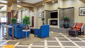 A lobby with blue sofas, a fireplace, and potted plants. - Comfort Suites Batesville (Batesville)
