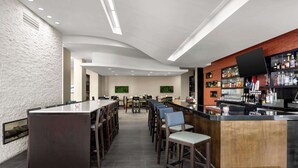 A modern bar area with a long counter, multiple seating options, and a variety of bottles and glasses on shelves. - Embassy Suites Newark Airport (Elizabeth)