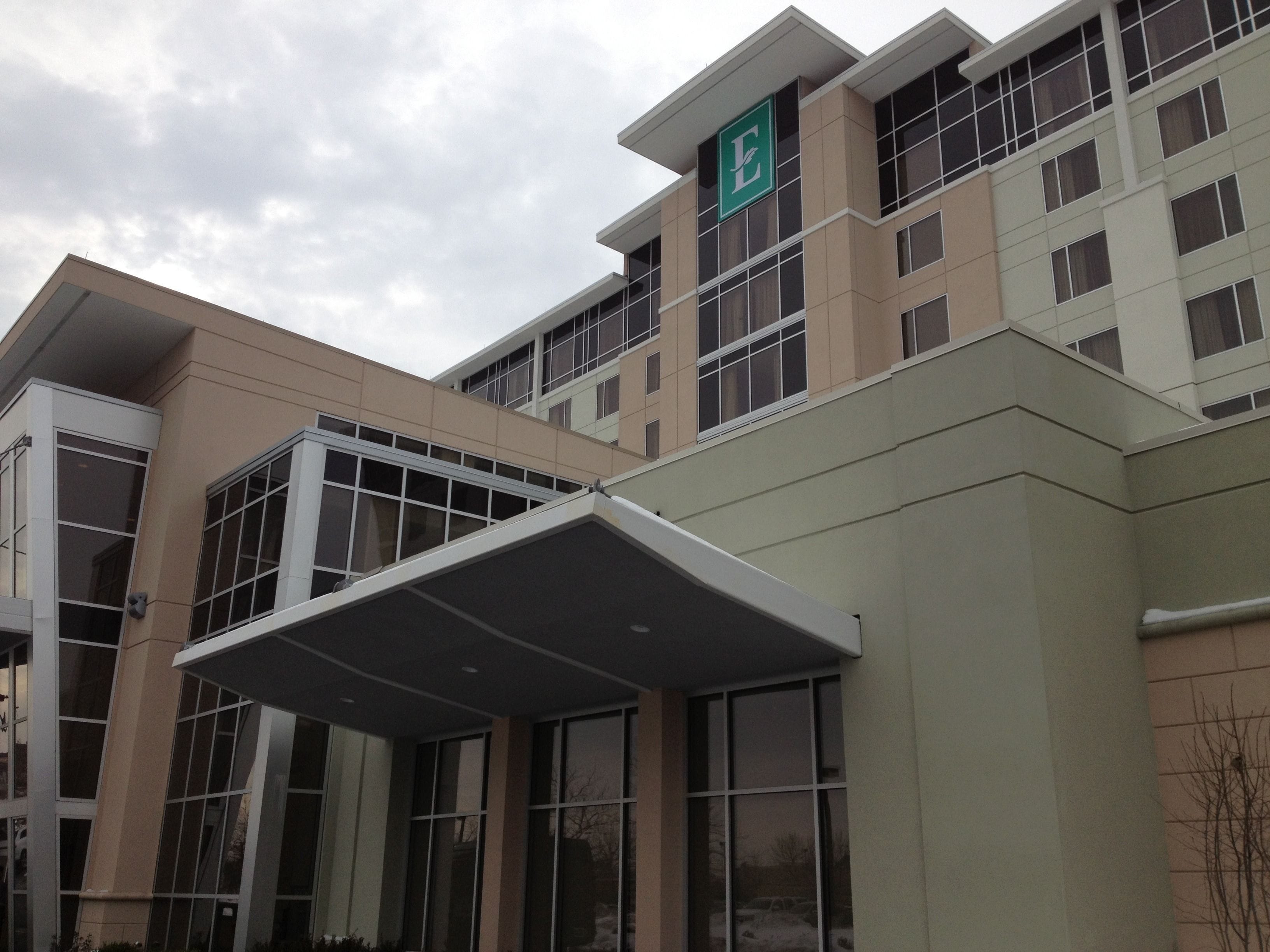 A multi-story building with a prominent 'E' logo on the facade, large windows, and a covered entrance area.