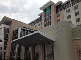A multi-story building with a prominent 'E' logo on the facade, large windows, and a covered entrance area.
