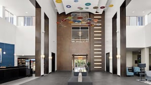 A spacious lobby with a modern design, featuring a reception desk, seating area, and a unique ceiling decoration. - Embassy Suites Newark Airport (Elizabeth)