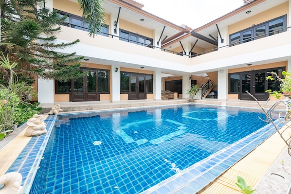 A swimming pool with a tiled floor, surrounded by a building with multiple balconies and windows.
