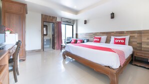 A hotel room with a large bed, wooden headboard, and a desk with a chair. - Chaba Garden Resort & Service (Pattaya)