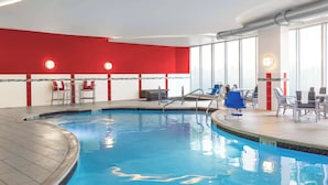 Una piscina interna con decorazioni a tema rosso e bianco, zone relax e ampie finestre.