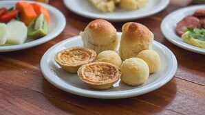 A table with plates of food, including bread rolls and a glass of orange juice. -  Pousada Porto Verano (Ipojuca)