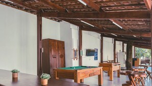 A pool table in a room with wooden benches and a potted plant. -  Pousada Porto Verano (Ipojuca)
