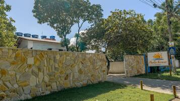A stone wall, a grassy area, and a sign with a sun and water graphic.