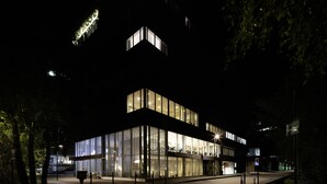 Een modern gebouw met grote glasramen en een opvallende torenstructuur.