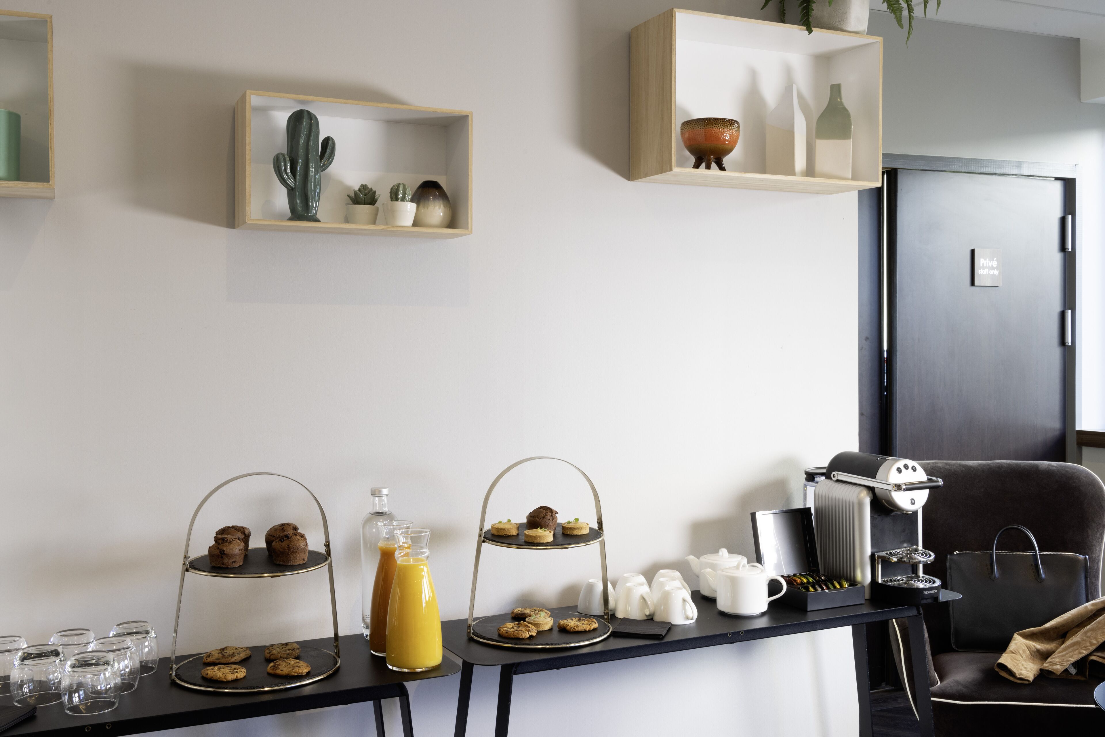 A breakfast setup with a coffee machine, tea set, and a two-tiered dessert stand.