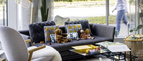 A modern living room with a grey sofa, a white chair, and a glass coffee table.