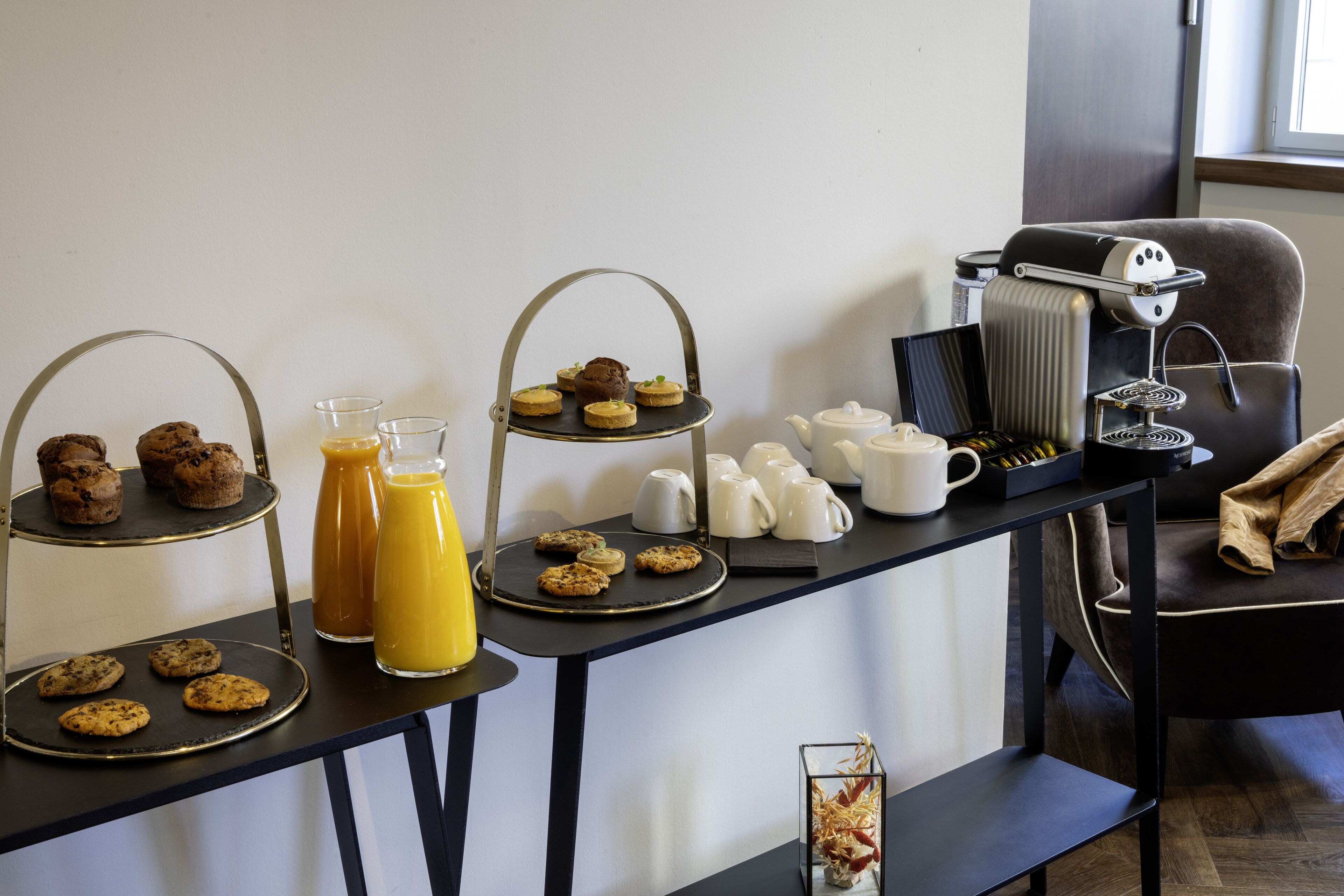 A breakfast buffet setup with various pastries, muffins, and coffee-making equipment.