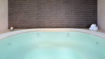 Relax in a serene hot tub surrounded by a light-colored floor and dark brick wall.