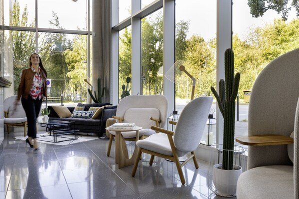 Una sala moderna con un sofá, sillas, una mesa de centro y un cactus.