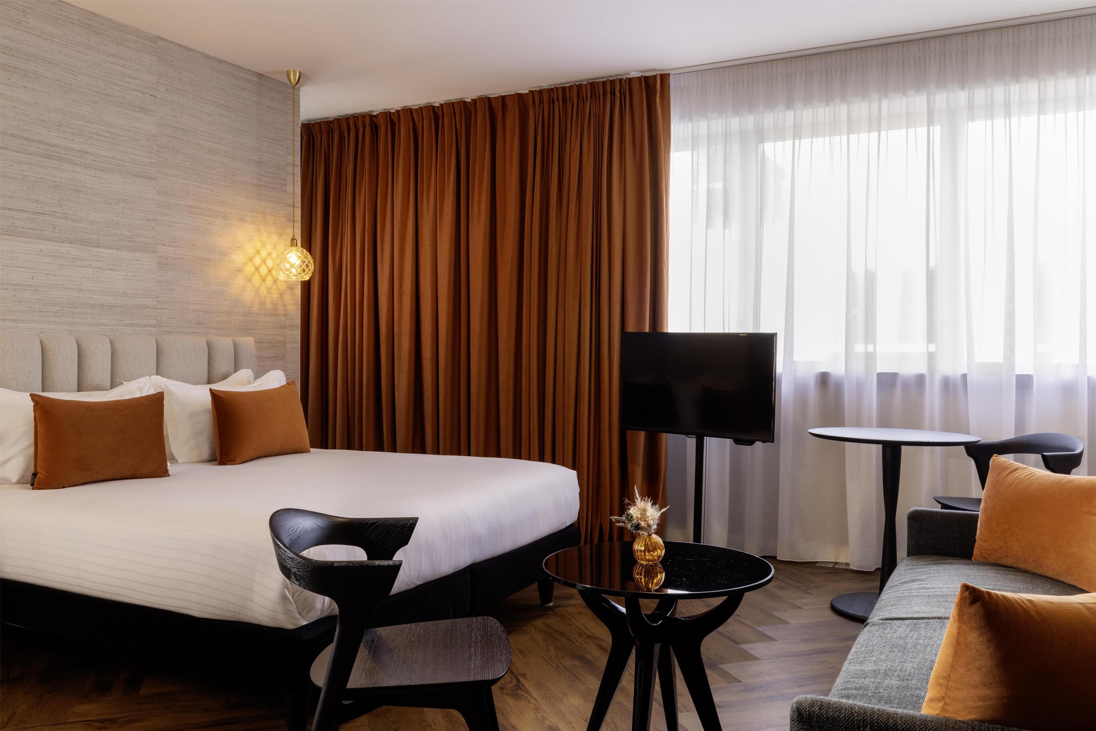 A hotel room with a large bed, a sofa, a TV, and a small table.