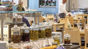 A buffet area with various food items in glass containers, a rolling pin, and plates on a counter. - Akti Palace Hotel - All inclusive (Kos)