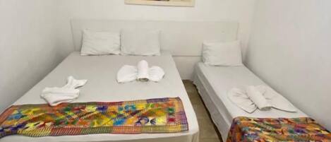 Una habitación con dos camas, cada una con una manta colorida y ropa de cama blanca.