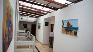 A hallway with artwork on the walls, a staircase, and a view of the ocean through a window. - Pousada Nossa Casa (Maceió)