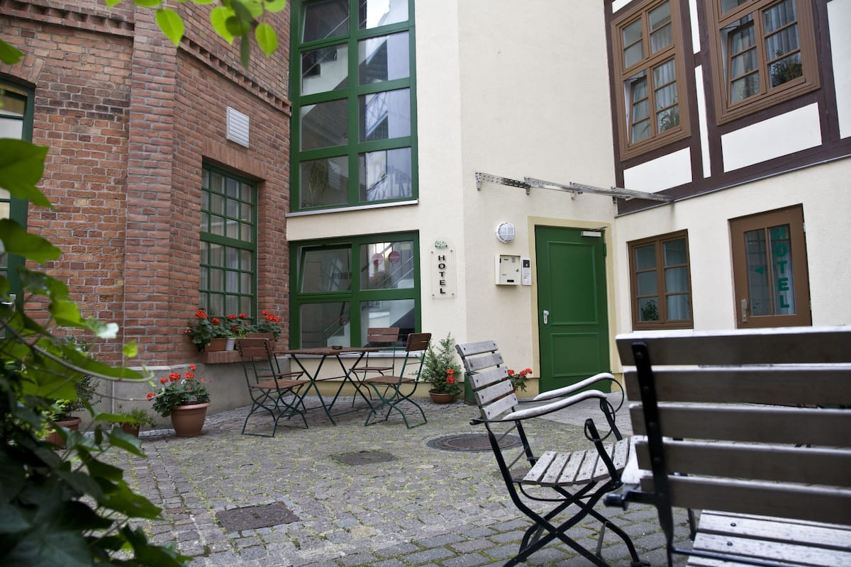 A courtyard with a brick building, a green door, and a bench.