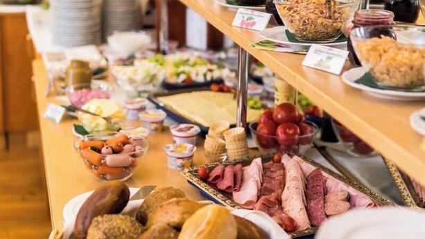 Un bufé con distintos alimentos y una cesta de pan.