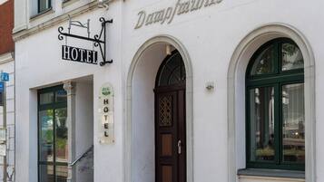 Un hotel con una facciata classica, un evidente cartello con la scritta 'HOTEL' e un ingresso ad arco.
