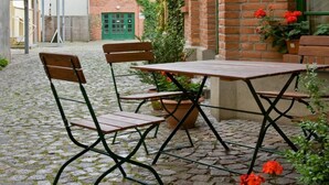 Un patio con una mesa y sillas, rodeado de edificios de ladrillo y follaje.