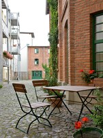 Un patio con una mesa y sillas, rodeado de edificios de ladrillo y follaje.