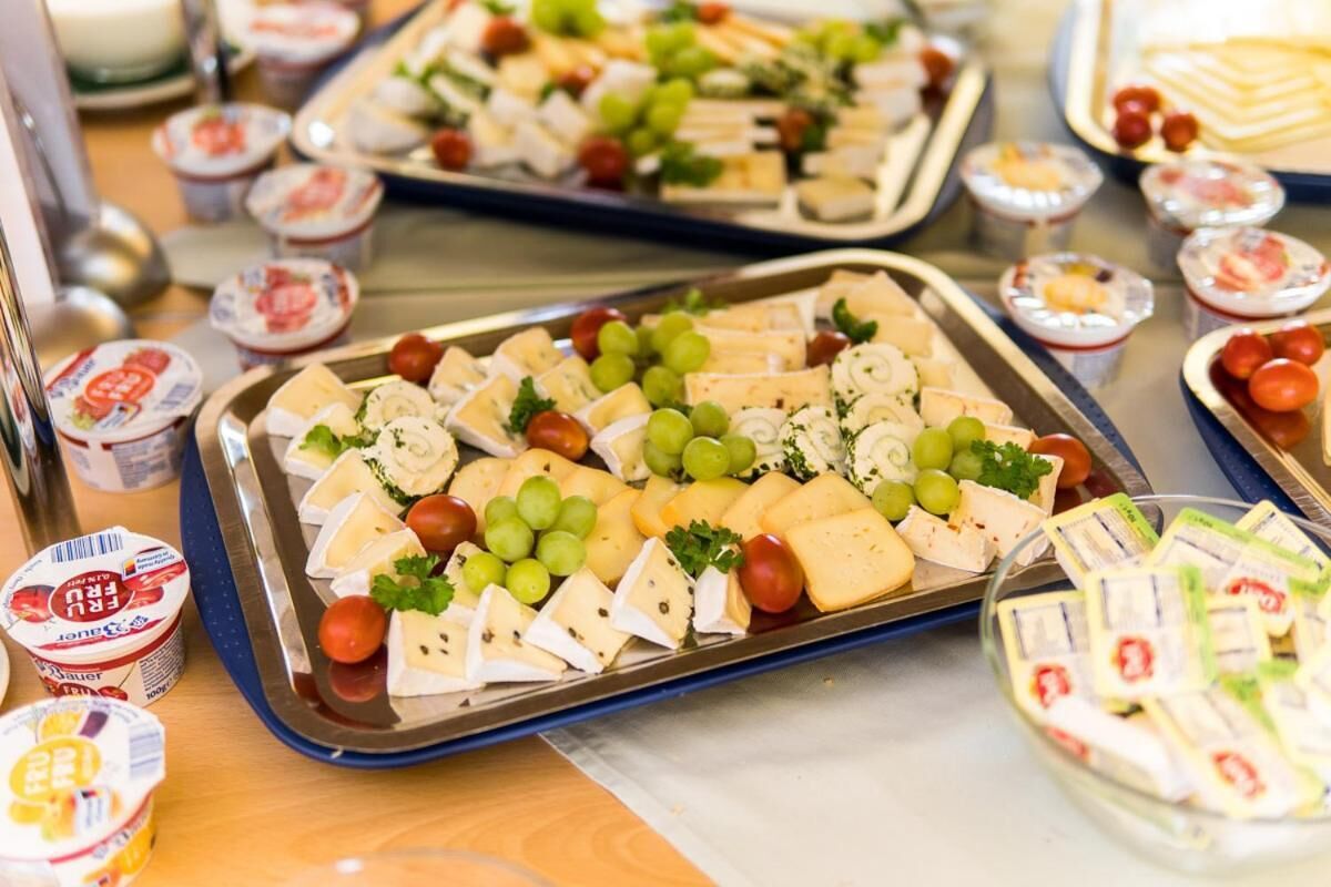 Une table de buffet avec divers fromages, des raisins et de petits récipients contenant des sauces.