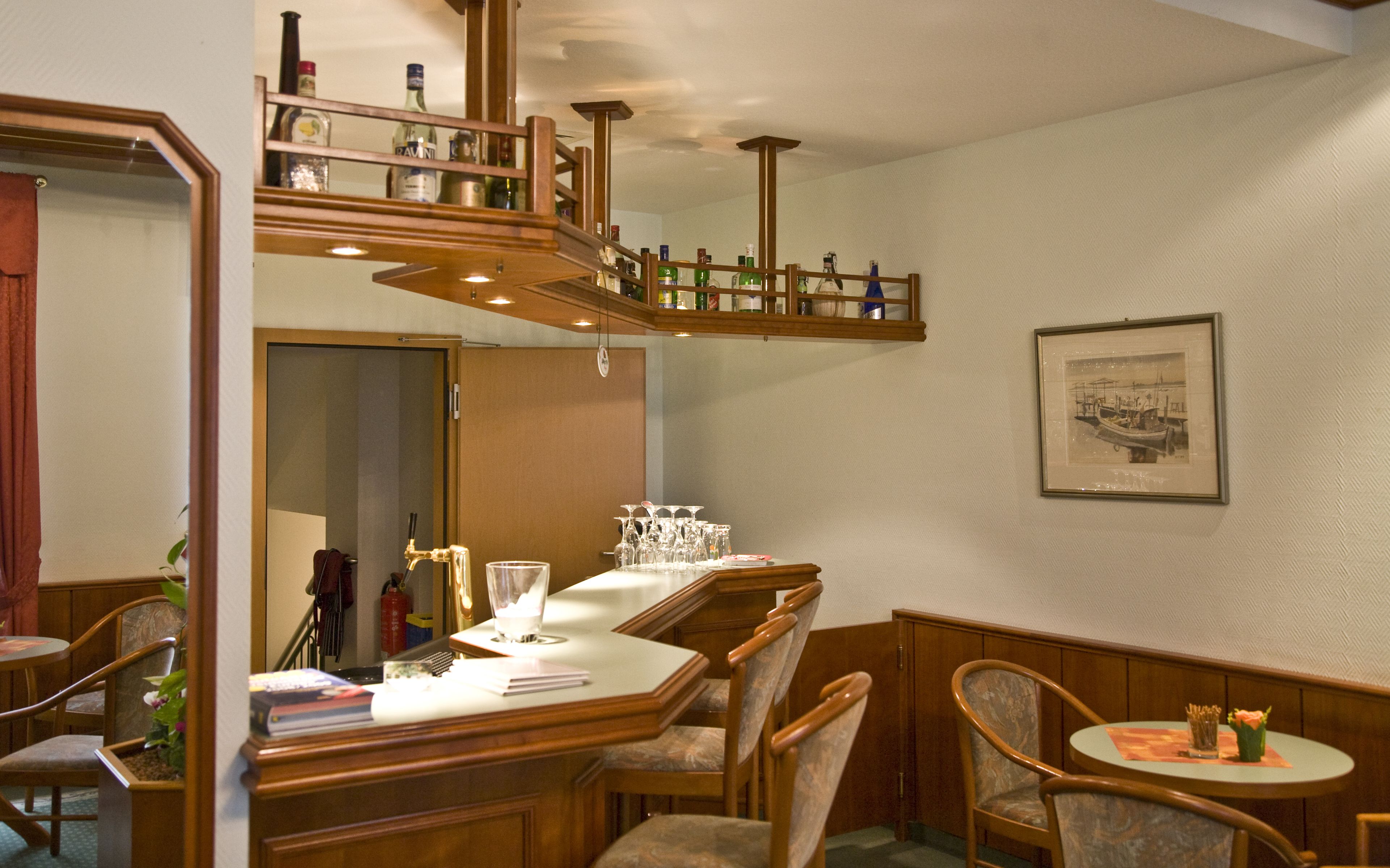 A dining area with a wooden table, chairs, and a bar area with bottles.