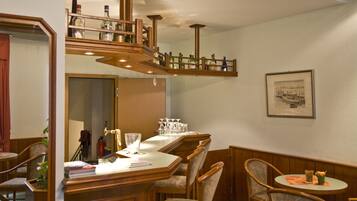A dining area with a wooden table, chairs, and a bar area with bottles.