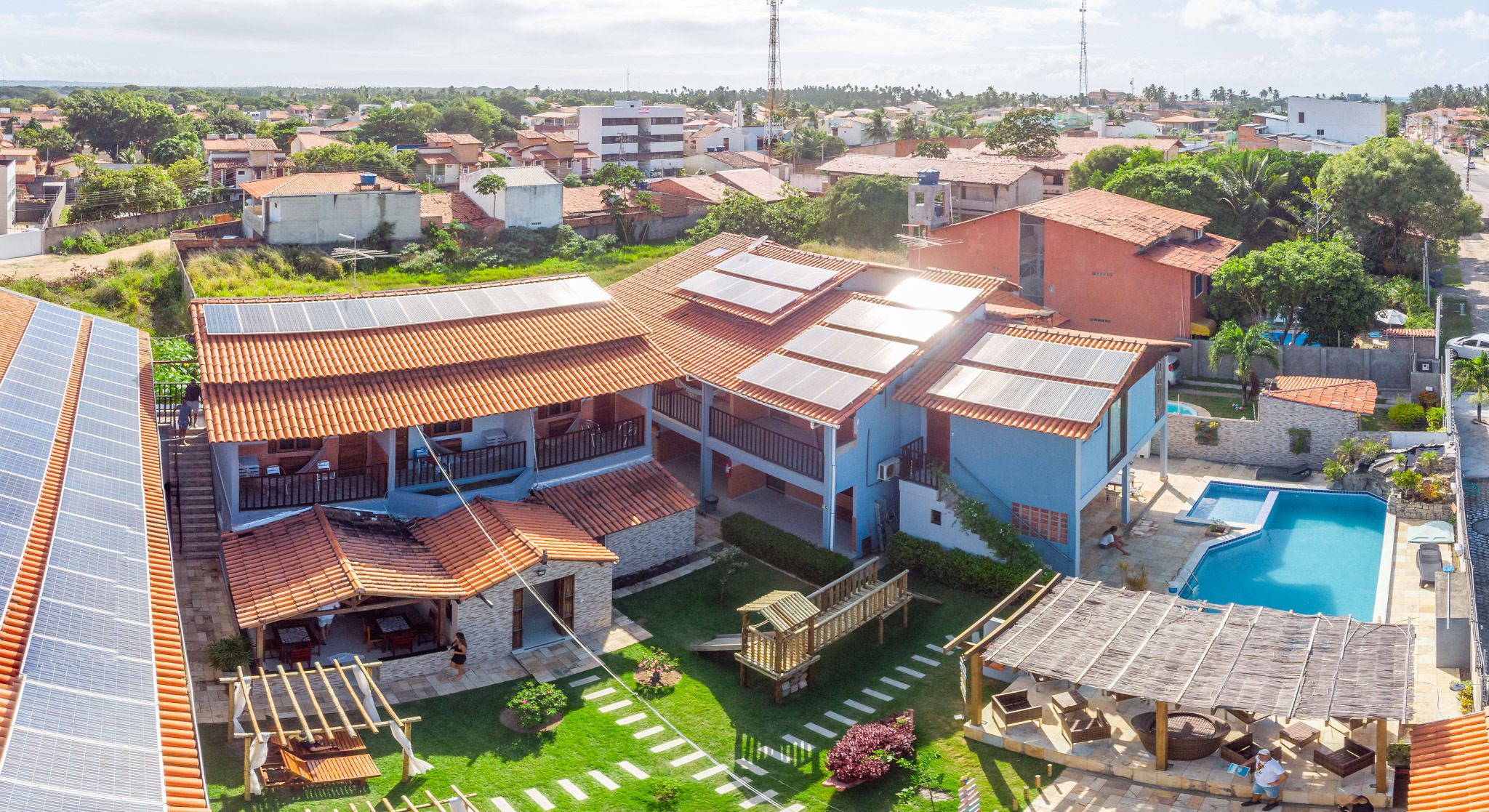 Ein Wohngebäude mit Schwimmbad, Solaranlage und einem gepflegten Garten.