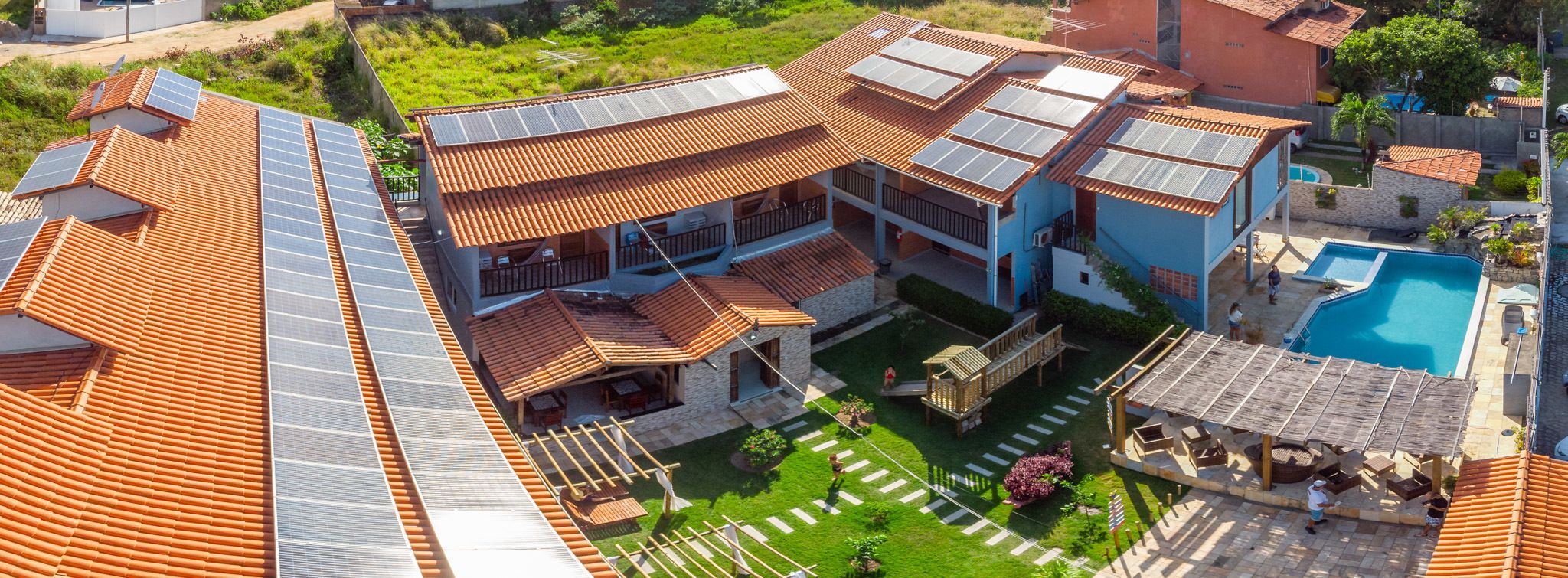 Una amplia villa con varios niveles, piscina y paneles solares en el techo.