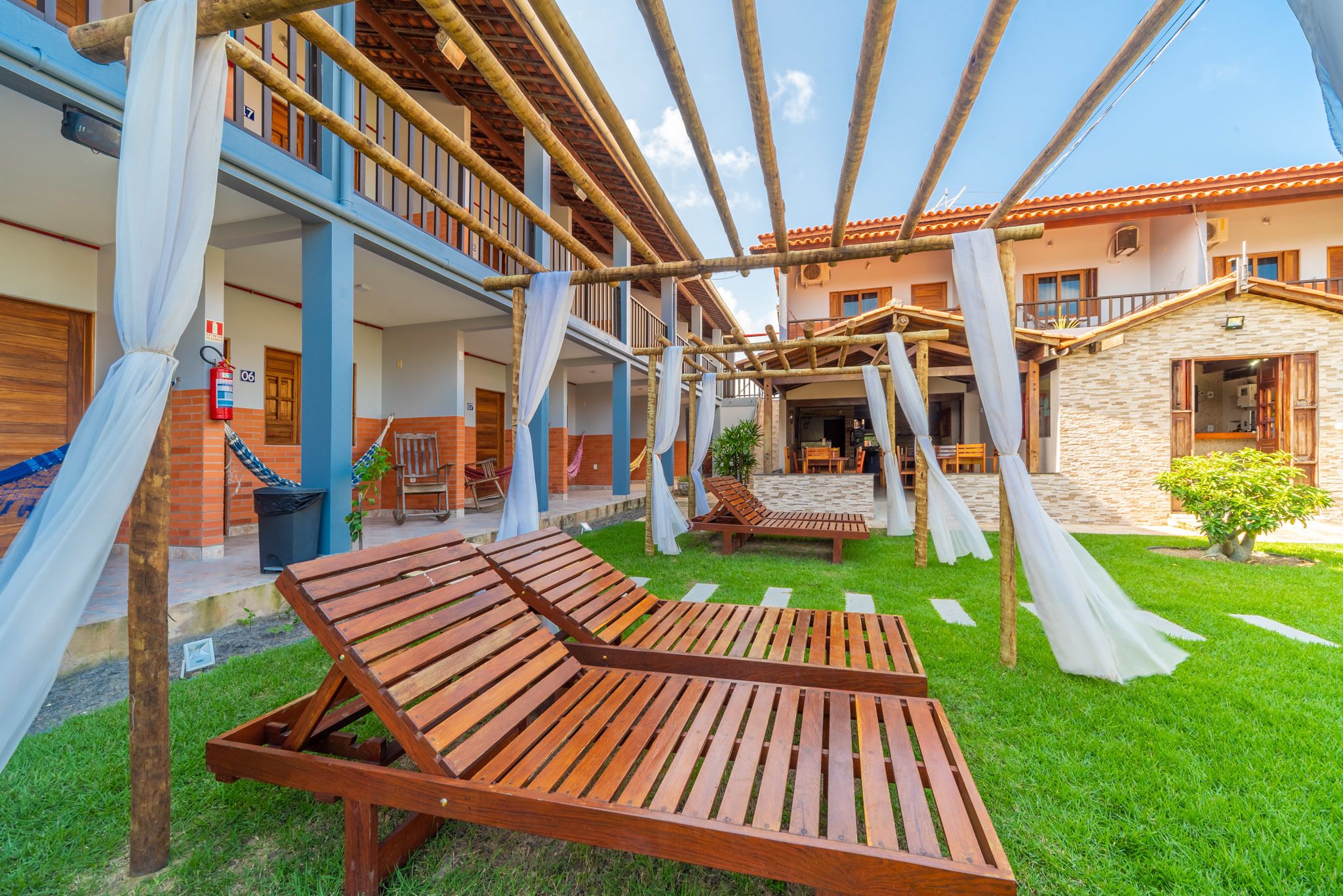 A courtyard with wooden lounge chairs, a fire extinguisher, and a covered seating area.