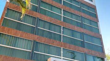 A modern hotel building with a prominent logo, large windows, and a reception area with a sign.