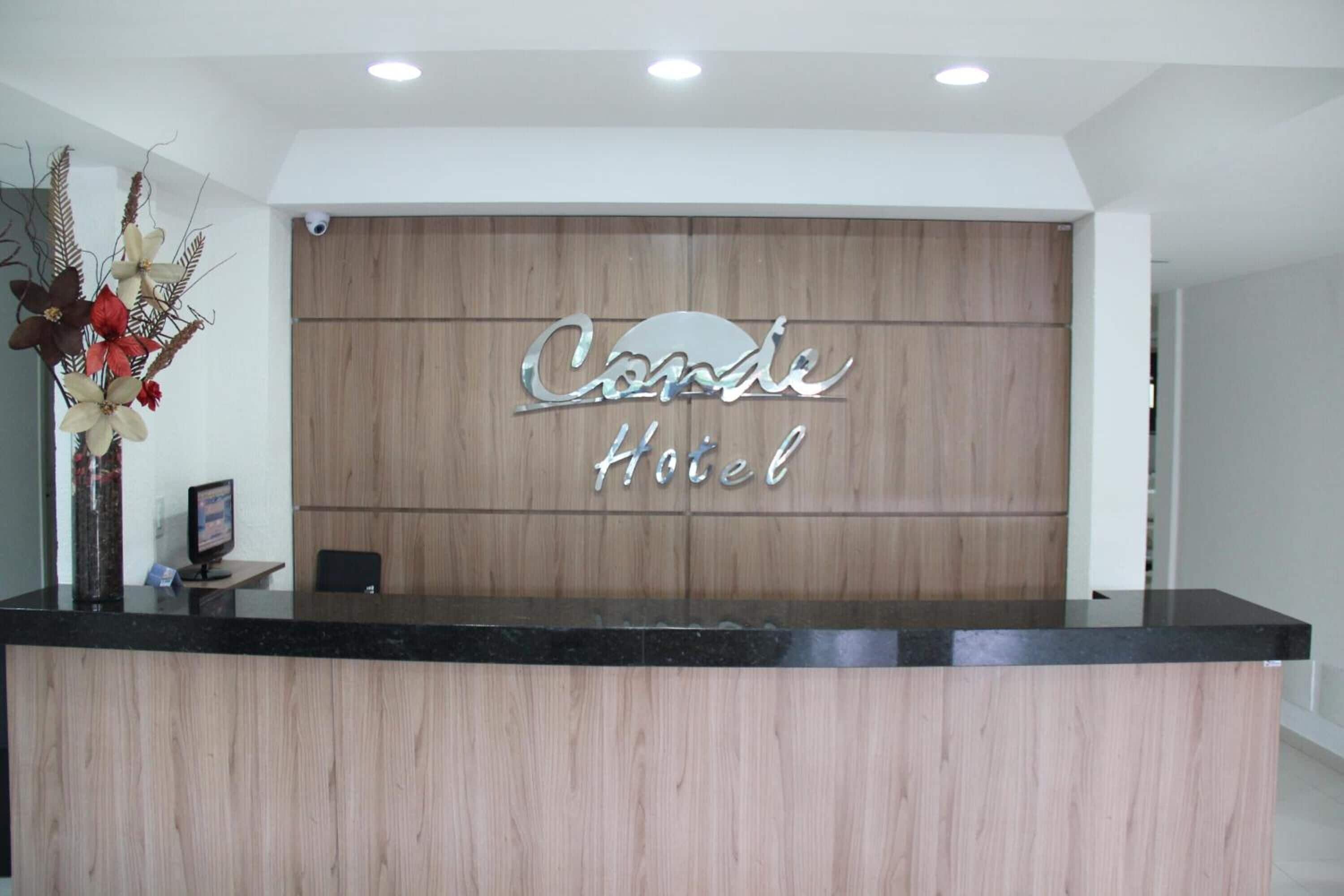 Mostrador de recepción de hotel con un fondo de paneles de madera y un cartel que dice "Cande Hotel".