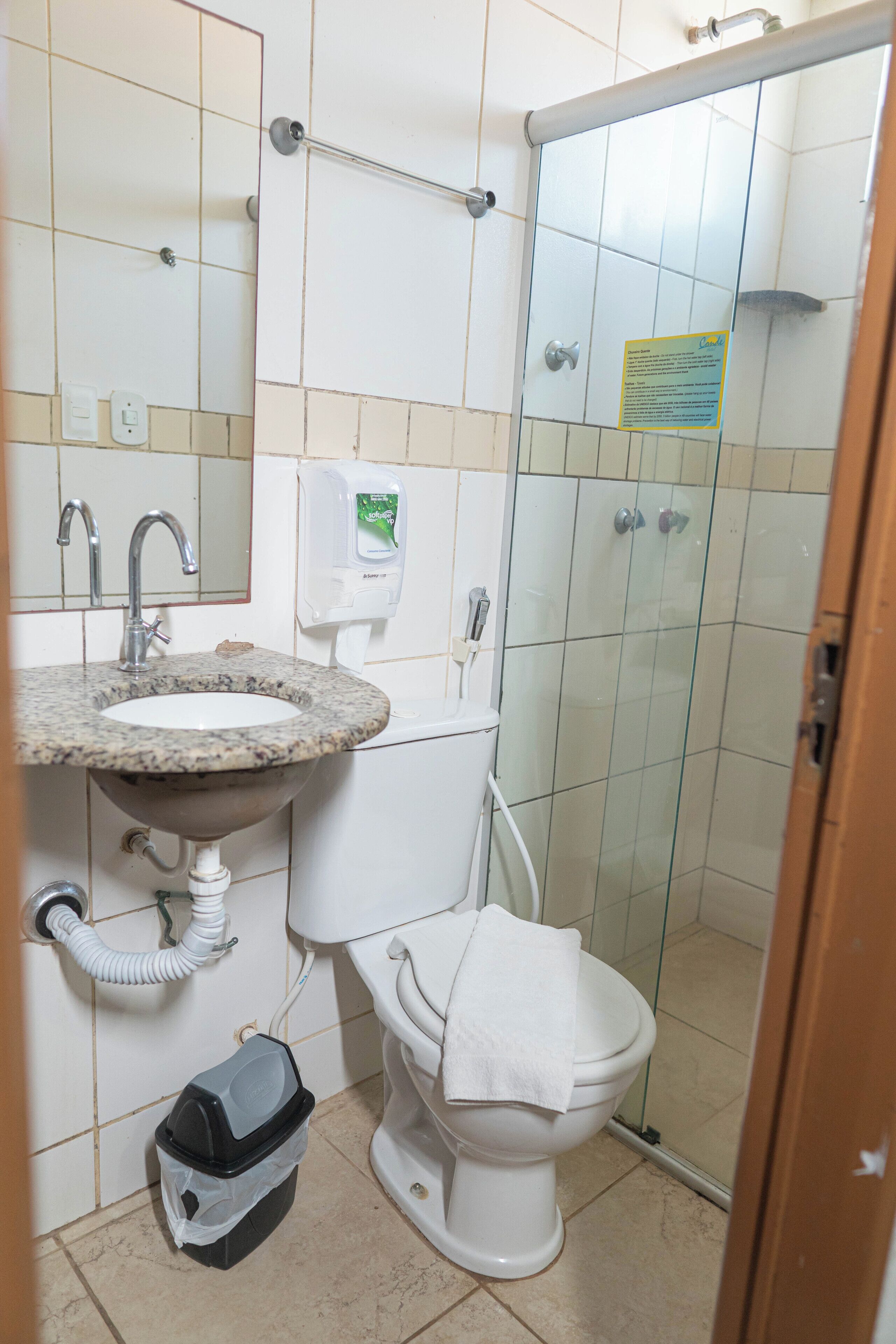 Un baño con lavamanos de granito, inodoro blanco y cabina de ducha de vidrio.
