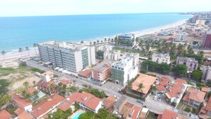 Eine Luftaufnahme einer Küstenstadt mit einer Mischung aus Wohn- und Geschäftsgebäuden, einem Strand und freier Sicht auf den Ozean.