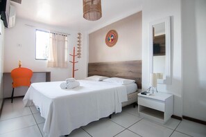 Habitación de hotel con cama, escritorio, silla, espejo y ventana con cortinas.