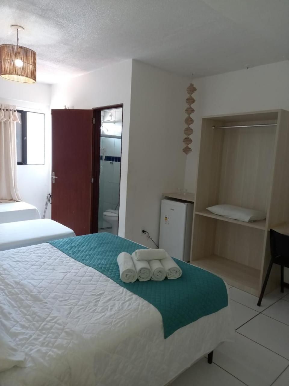 A hotel room with a bed, a desk, a wardrobe, and a small refrigerator.