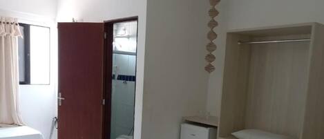 A hotel room with a bed, a desk, a wardrobe, and a small refrigerator.