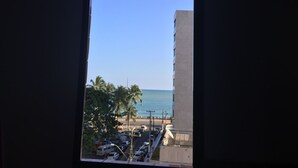 A view through a window of a parking lot with a building and palm trees in the foreground, and a clear blue sky above. - Hotel Pousada Gogo da Ema (Maceió)