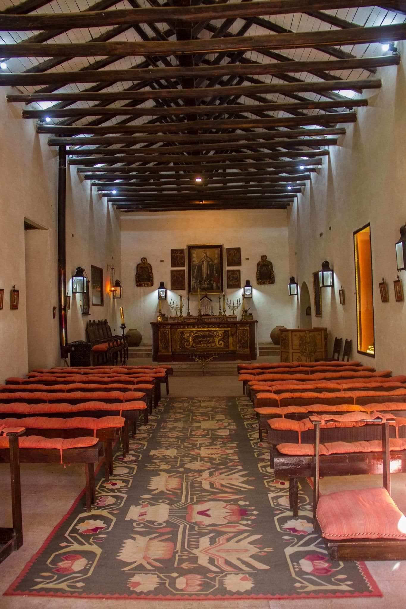 A church interior with rows of pews, a central altar, and religious artwork on the walls.