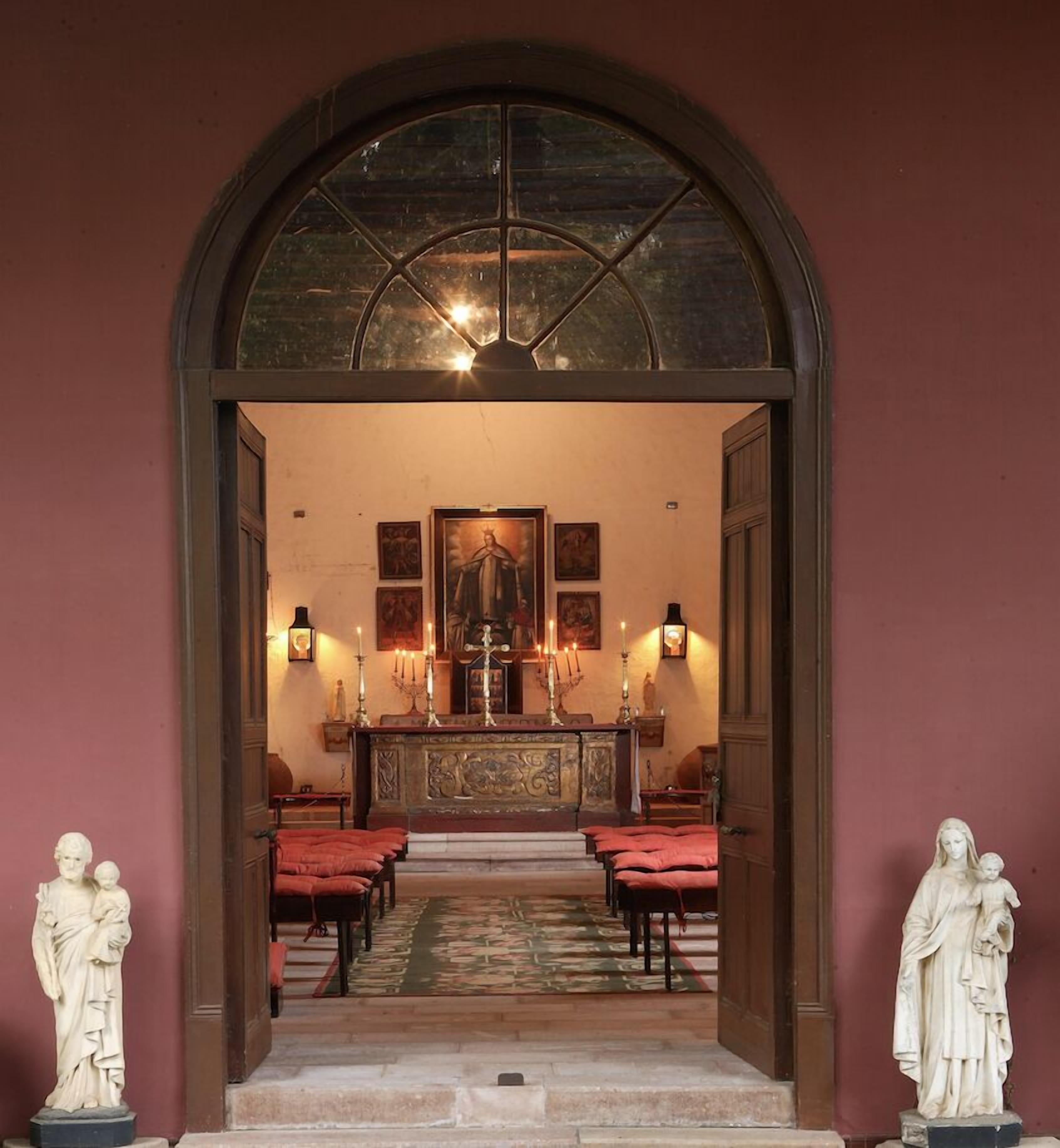 En buet indgang til et kapel med et midteraltar, stearinlys og religiøse statuer.