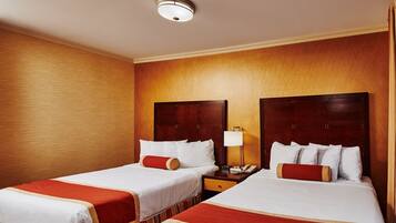 A hotel room with two beds, each with a wooden headboard, a nightstand with a lamp, and a ceiling light.